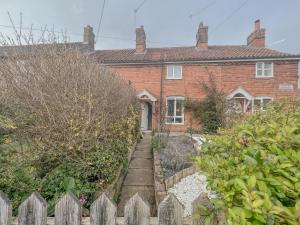 a brick house with a fence in front of it at Quaint 2 bed cottage near North Norfolk Coast - Harpers Cottages in Syderstone