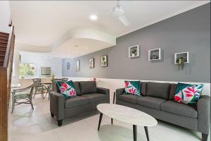 een woonkamer met 2 banken en een tafel bij Lovely Spacious 2 Bedroom 2 Bathroom Townhouse in Resort in Port Douglas