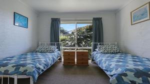 2 Betten in einem Zimmer mit Fenster in der Unterkunft Unit 3 18 Surf Circle Tura Beach in Tura Beach