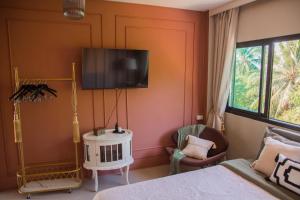 a bedroom with a bed and a tv on the wall at Sunset Hilltop Ocean View 2bd House in Haad Tian