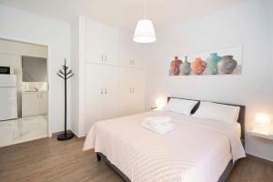 - une chambre blanche avec un lit blanc et des serviettes dans l'établissement Filoxenia MG city center, à Athènes