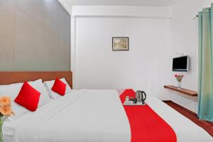 a bedroom with a white bed with red pillows at OYO Hotel Jayam Ooty Residency in Ooty