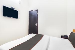1 dormitorio con 1 cama y puerta con TV en Hotel Mk Grand, en Patna