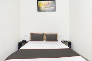 ein Schlafzimmer mit einem weißen Bett mit zwei braunen Kissen in der Unterkunft Hotel Mk Grand in Patna
