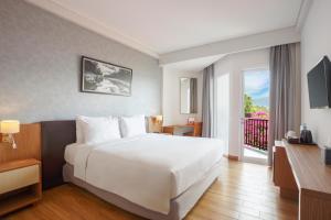 a hotel room with a large white bed and a balcony at Swiss-Belinn Luwuk in Luwuk