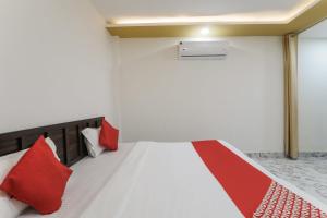 Schlafzimmer mit einem Bett mit roten und weißen Kissen in der Unterkunft OYO Hotel Aastha Near Chaudhary Charan Singh International Airport in Bijnaur