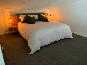 un grande letto bianco in una stanza con due lampade di Yarra Valley Stables Retreat a Gruyere