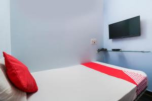 a bedroom with a bed with red pillows and a flat screen tv at Flagship Shree Raksha Comforts in Devanhalli