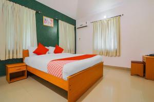 1 dormitorio con 1 cama con almohadas rojas en The Goan Courtyard, en Colva