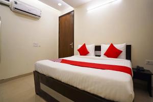 a bedroom with a large bed with red pillows at Hotel Olive Saffron in New Delhi