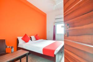a bedroom with orange walls and a bed and a wooden door at Flagship New Cresent Park in Irugūr