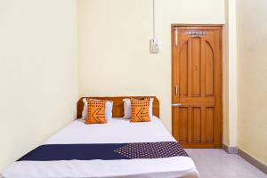 a bedroom with a bed and a wooden door at OYO Shivaye Rest House in Deoghar