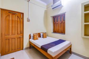 een kleine slaapkamer met een bed en een houten deur bij OYO Shivaye Rest House in Deoghar