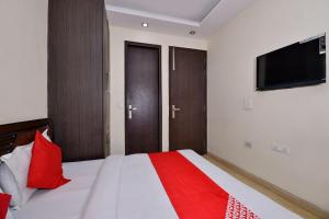 1 dormitorio con 1 cama con almohadas rojas y TV de pantalla plana en OYO Capital O Hotel Lotus B&B, en Nueva Delhi