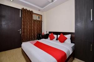 1 dormitorio con 1 cama grande con almohadas rojas en OYO Capital O Hotel Lotus B&B, en Nueva Delhi