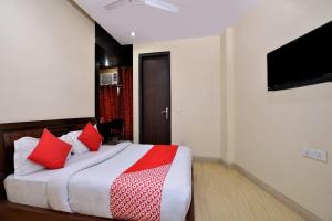 a bedroom with a bed with red pillows and a flat screen tv at OYO Capital O Hotel Lotus B&B in New Delhi