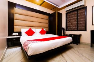 1 dormitorio con 1 cama grande con almohadas rojas en Hotel J P Inn Near Patel Nagar Metro Station, en Nueva Delhi