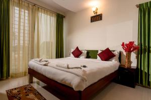 a bedroom with a large bed with red and green curtains at Seasons Suites in Bangalore