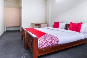 a bedroom with a large wooden bed with red pillows at Appas Residency in Ambalavayal