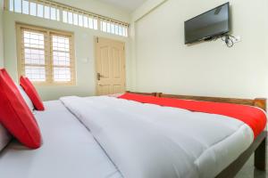 sypialnia z 2 łóżkami z czerwonymi poduszkami i telewizorem w obiekcie Appas Residency w mieście Ambalavayal