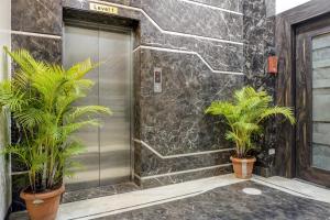 a elevator with two palm trees in front of a wall at Super Townhouse OAK Regal Inn Near Sant Tukaram Nagar Metro Station in Chinchwad