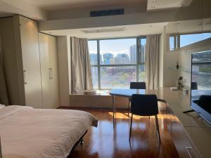 北京的住宿－Beijing Elegant Seasons Park Apartment，一间卧室配有一张床、一张桌子和一个窗户。