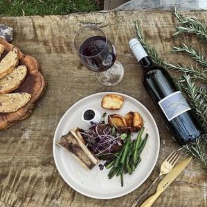 Sarabah Estate Vineyard & Villa في Beechmont: طبق من الطعام على طاولة مع زجاجة من النبيذ