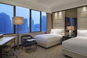a hotel room with two beds and a desk at Singapore Marriott Tang Plaza Hotel in Singapore