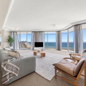 ein Wohnzimmer mit einem Sofa, einem TV und Fenstern in der Unterkunft Burleigh Surf Apartments in Gold Coast