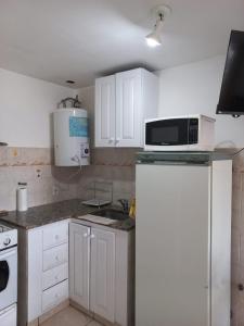 a kitchen with white cabinets and a microwave at Departamentos Centro Dpto 2 1 habitacion in Tandil