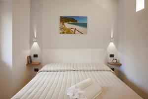 a white bedroom with a bed with towels on it at Affittacamere Somnium in Sirolo