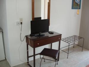 ein Schreibtisch mit einem Fernseher darauf und einem Stuhl in der Unterkunft Helena's Apartments in Manganari