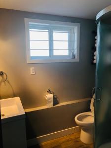 a bathroom with a toilet and a window at Cheerful home close to downtown Kelowna in Kelowna