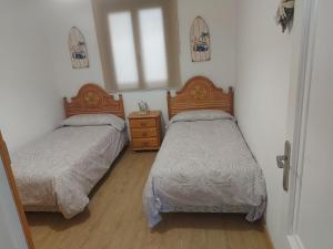 a bedroom with two beds and a dresser and a window at Piso Turístico Bahía San Vicente in San Vicente de la Barquera