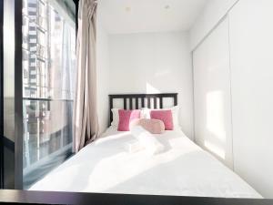 a bedroom with a bed with pink pillows and a window at MY80 Apartment located in the inner of Melbourne CBD in Melbourne