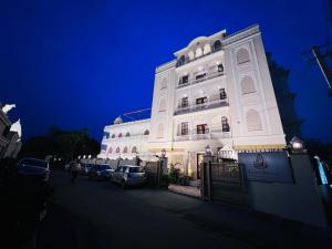 un bâtiment blanc avec des voitures garées devant lui dans l'établissement Laxmi Palace Heritage Boutique Hotel, à Jaipur