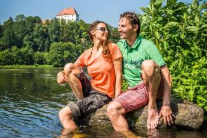 un hombre y una mujer sentados en una roca en el agua en Ferienwohnung Jobst - Ruhig mit Blick ins Grüne, en Nittenau