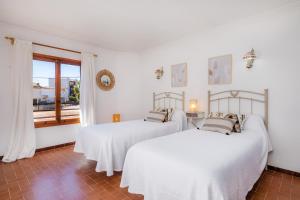 two beds in a white room with a window at Casa Can Pinyol in Cala Figuera
