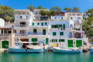 two boats in the water in front of houses at Casa Can Pinyol in Cala Figuera