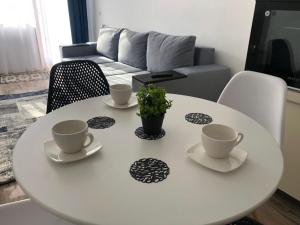 a white table with two cups and a plant on it at NARCISA in Piatra Neamţ