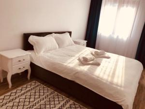 a bedroom with a white bed with a night stand and a window at NARCISA in Piatra Neamţ