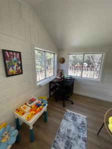a room with a table and a desk and two windows at Cozy House With Great Backyard in Frazier Park