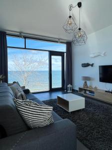 salon z kanapą i dużym oknem w obiekcie Apartment Morski Widok w Boulevard Ustronie Morskie w mieście Ustronie Morskie