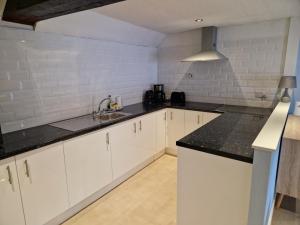 una cucina con armadietti bianchi e ripiani neri di Gorgeous 1 Bed Apartment in Wetwang a Great Driffield