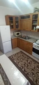 eine Küche mit Holzschränken und einem weißen Kühlschrank in der Unterkunft 3 комнатная квартира на Курмангазы - 3 room apartment on Kurmangazy in Atyrau