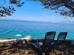 two chairs sitting next to the ocean with an umbrella at Vila Elena in Prigradica