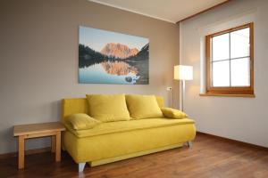 un sofá amarillo en una sala de estar con ventana en Sun Apartments - with Dolomiten Panorama, en Lienz