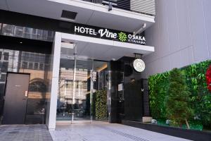 a hotel entrance with a sign on a building at HOTEL VINE OSAKA KITAHAMA in Osaka