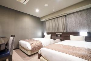 um quarto de hotel com duas camas e uma secretária em HOTEL VINE OSAKA KITAHAMA em Osaka