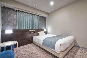 a bedroom with a bed and a table and a window at HOTEL VINE OSAKA KITAHAMA in Osaka